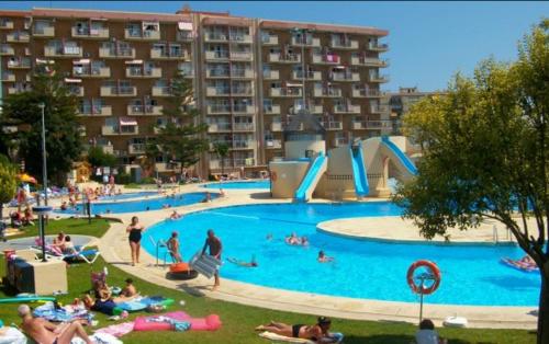 a large swimming pool with people laying in the grass at Jupiter Sea View in Benalmádena