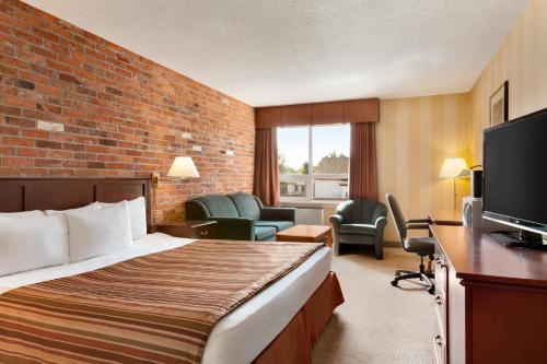 a hotel room with a bed and a television at Travelodge by Wyndham North Bay Lakeshore in North Bay