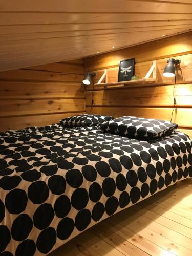 Cama grande en habitación con paredes de madera en Riverside Cottage Aalto Borealis en Keminmaa