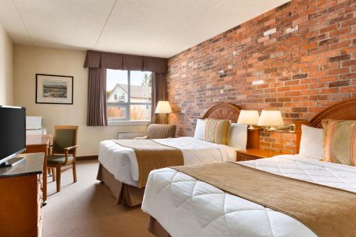 Habitación de hotel con 2 camas y pared de ladrillo en Travelodge by Wyndham North Bay Lakeshore, en North Bay