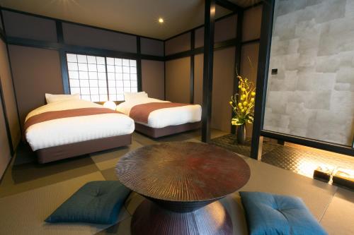 ein Hotelzimmer mit 2 Betten und einem Tisch in der Unterkunft Hosta Umekoji Miyabi in Kyoto