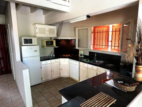a kitchen with a white refrigerator and white cabinets at Les Villas Créoles de Sainte-Anne in Sainte-Anne