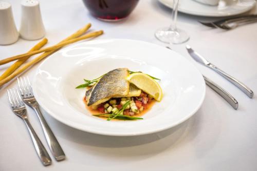 a white plate with a fish dish on a table at The Dostyk Hotel in Almaty