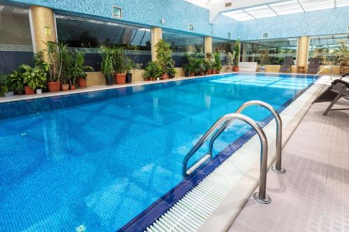 a large swimming pool in a building with plants at The Dostyk Hotel in Almaty