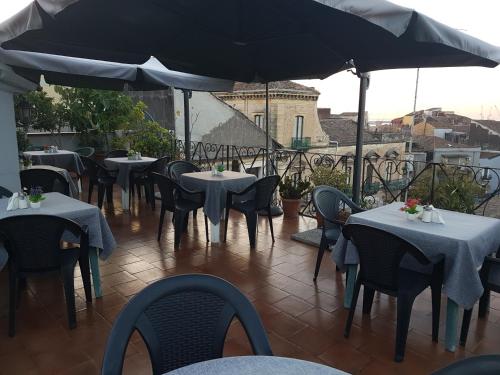 a patio with tables and chairs and an umbrella at Hotel Biscari in Catania