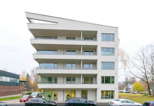 un bâtiment blanc avec des voitures garées devant lui dans l'établissement Fortuuna 5 Apartment, à Tartu