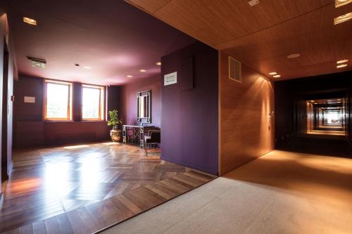 a room with a hallway with purple walls and wooden floors at The Dostyk Hotel in Almaty