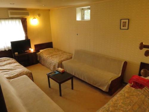 un soggiorno con 2 letti e un divano di Nikko Pension L'escale a Nikko