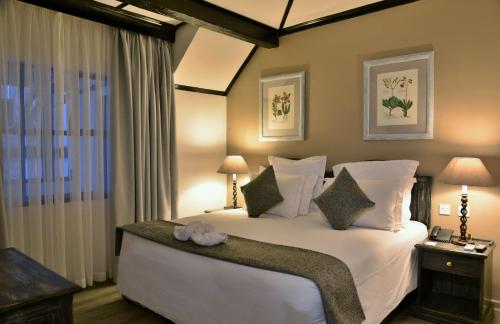 una camera da letto con un grande letto bianco con due lampade di Cresta Churchill Hotel a Bulawayo
