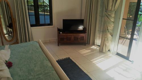 a living room with a television and a tiled floor at Chalets de Palma in La Digue