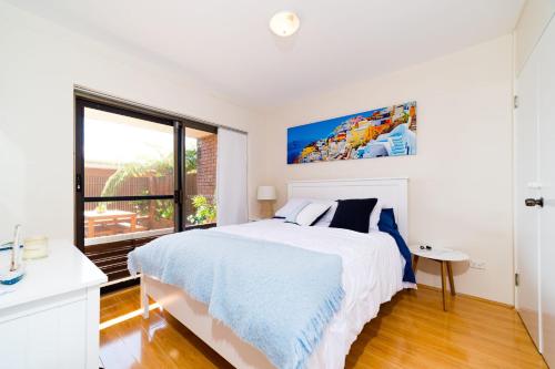a white bedroom with a large bed and a window at Joy's Hideaway in Terrigal