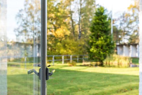 a door knob on a glass window with a yard at Hotell Solhem Park in Borås