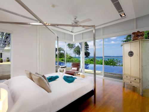 een slaapkamer met een wit bed en uitzicht op de oceaan bij Villa Sapna by Elite Havens in Ban Pa Khlok