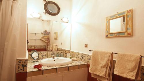 bagno con lavandino, specchio e asciugamani di Lalli House by DomuSicily a Cefalù