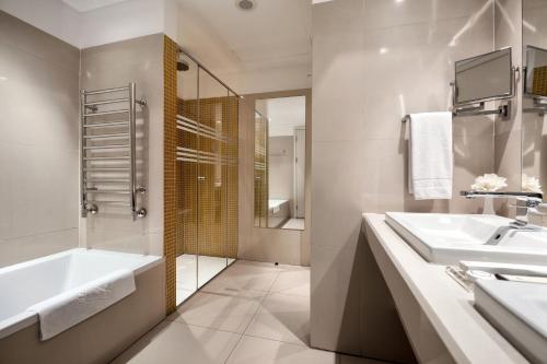 a bathroom with a tub and a sink and a shower at The Dostyk Hotel in Almaty
