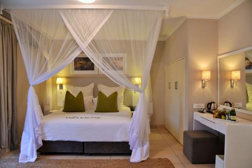 a bedroom with a canopy bed with green pillows at Cresta Sprayview Victoria Falls in Victoria Falls