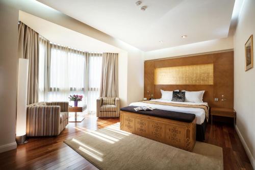 a bedroom with a king sized bed and a chair at The Dostyk Hotel in Almaty