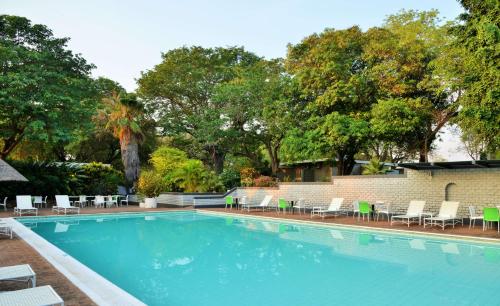 a large swimming pool with chairs and trees at Cresta Sprayview Victoria Falls in Victoria Falls
