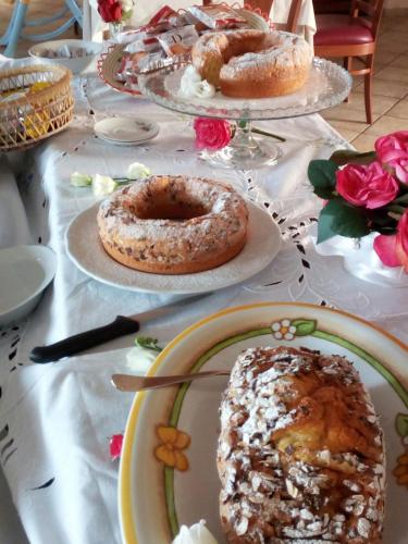 Una mesa cubierta con platos de pasteles y tartas. en Villa Loreto, en Alghero