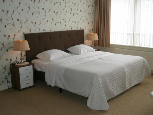een slaapkamer met een groot bed en een wit dekbed bij Hotel Excelsior in Den Haag
