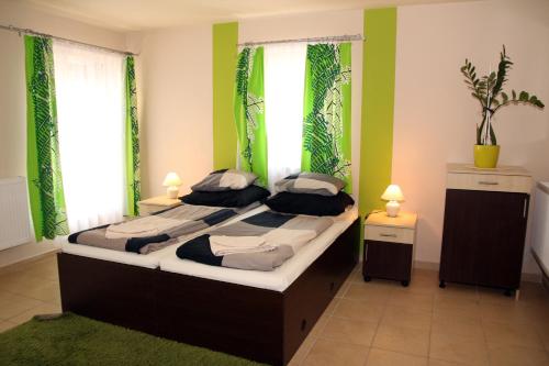 um quarto com 2 camas, paredes verdes e janelas em Írisz Apartmanház em Mórahalom