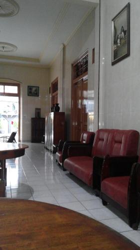 a waiting room with red chairs and a table at Hotel Paviljoen in Surabaya
