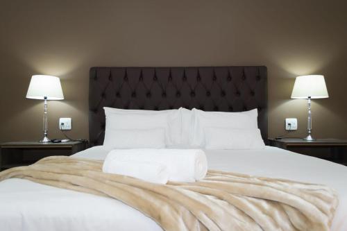 a bedroom with a large white bed with two lamps at Tuscany Vryburg in Vryburg