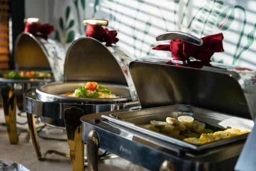 a row of buffet tables with food in trays at Asian Ruby Center Point Hotel & Spa in Ho Chi Minh City