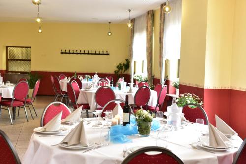 a dining room with white tables and red chairs at Schützenhof in Neuhof