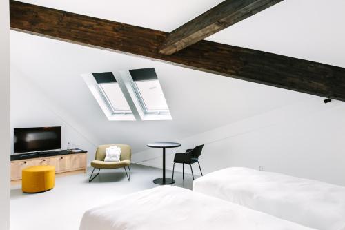 a bedroom with two beds and a tv and a table at TRUST Hotel in Beveren