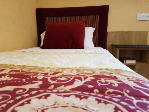 a bed with a red pillow on top of it at Shap Wells Hotel in Shap