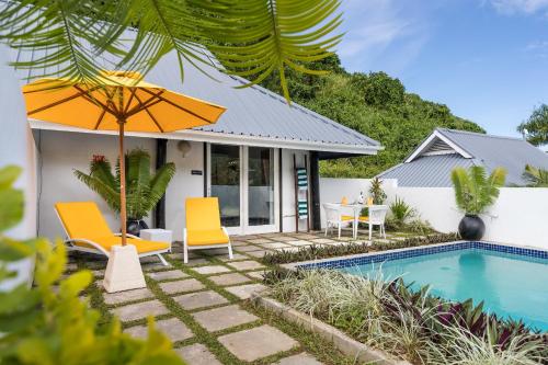 a house with a swimming pool and two chairs and an umbrella at Wellesley Resort Fiji in Vunaniu
