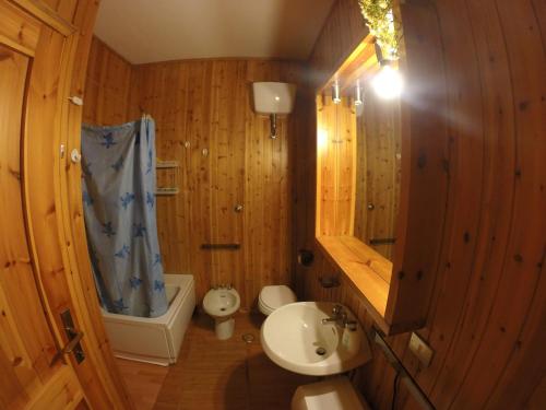 baño con paredes de madera, lavabo y aseo en Quadrifoglio, en Campo di Giove