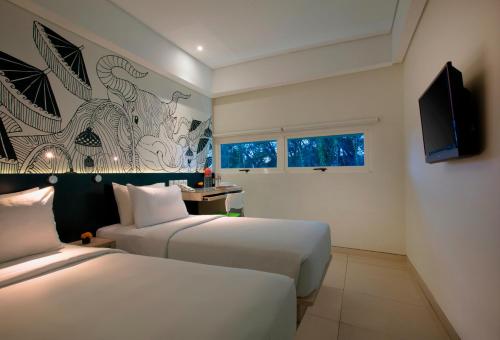 Habitación de hotel con 2 camas y TV de pantalla plana. en Grandmas Plus Hotel Airport en Kuta