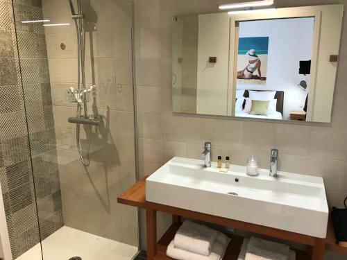 a bathroom with a sink and a shower at Centre Ville Location in La Rochelle