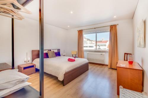 ein Schlafzimmer mit einem Bett und einem großen Fenster in der Unterkunft Cosmopolis in Lissabon