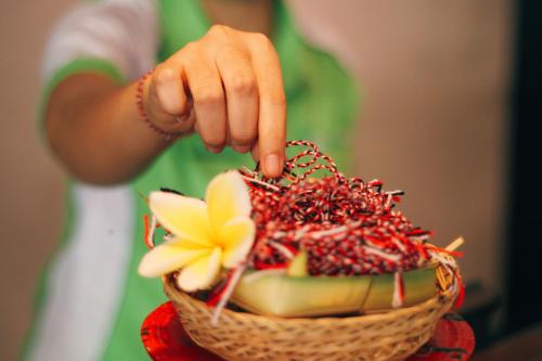 a person holding a basket filled with fruit at Grandmas Plus Hotel Airport in Kuta
