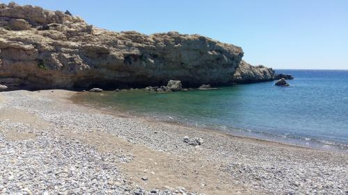 a beach with a rocky shore and the ocean at Lagos Studios & Apartments in Palekastron