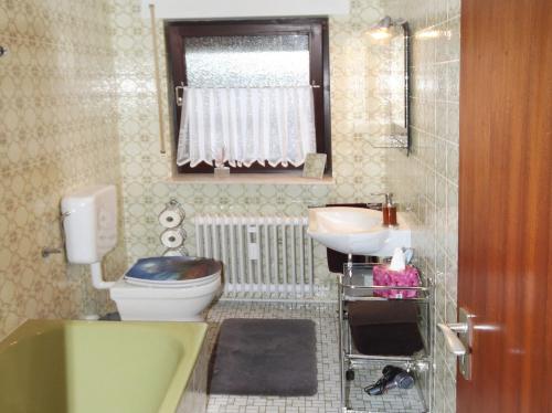 een badkamer met een toilet, een wastafel en een bad bij Ferienwohnung Buedinger Weg in Gründau