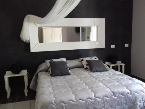 - une chambre avec un grand lit blanc et un miroir dans l'établissement Giardini di Marzo, à Felline
