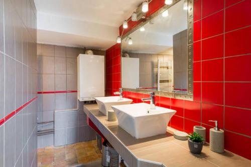 La salle de bains est pourvue de 2 lavabos et d'un mur rouge. dans l'établissement Loft coeur du Vieux Lyon, à Lyon