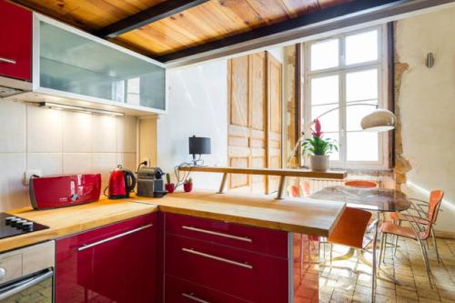 une cuisine avec des armoires rouges et une grande fenêtre dans l'établissement Loft coeur du Vieux Lyon, à Lyon