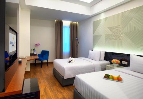 a hotel room with two beds and a flat screen tv at Golden Tulip Essential Makassar in Makassar