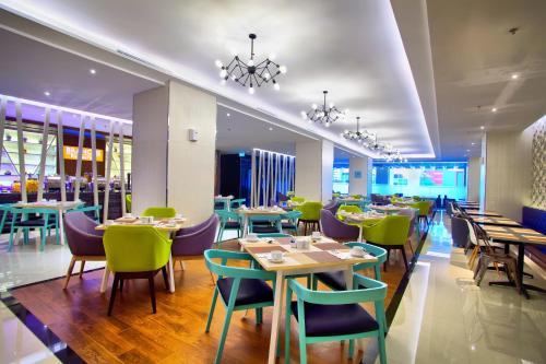 um restaurante com mesas e cadeiras num quarto em Golden Tulip Essential Makassar em Makassar