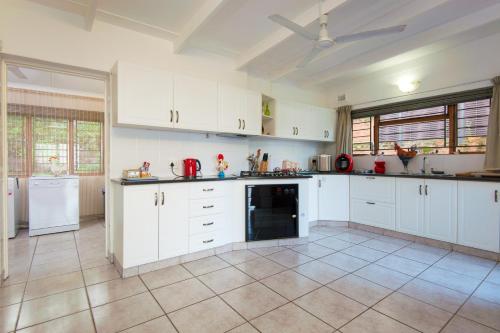 a kitchen with white cabinets and a tile floor at Ruby Sands Exclusive Holiday home in Ballito