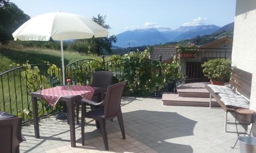 stół i krzesła z parasolem na patio w obiekcie B&B RAINA w mieście Castelfondo