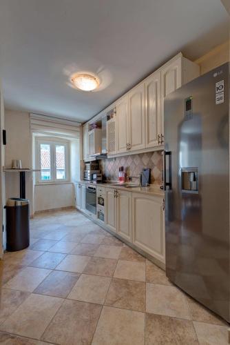 a large kitchen with white cabinets and a stainless steel refrigerator at Kotor old town Palace Bucha in Kotor