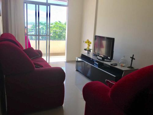 sala de estar con 2 sillas rojas y TV en Lindo e espacoso apartamento - Aracaju, en Aracaju