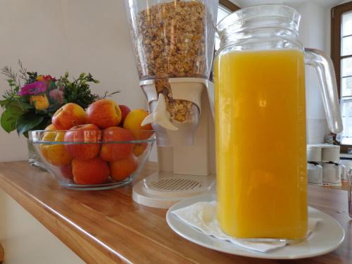 een glazen kan met sinaasappelsap naast een fruitschaal bij Gästehaus Am Hothertor in Görlitz