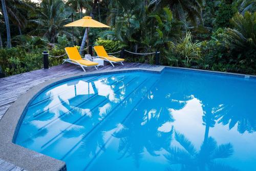 a swimming pool with two chairs and an umbrella at Wellesley Resort Fiji in Vunaniu